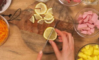 Как приготовить классическую сборную мясную солянку с колбасой, солеными огурцами и картошкой? Освободив лук от шелухи, промываем и крошим кубиком. Почищенные картофельные клубни разрезаем на кубики. Заливаем водой, чтобы не потемнел. Очистив морковь, промываем и крупно натираем на терке. Колбасу нарезаем не слишком крупно. Моем лимон и нарезаем кружочками, а затем режем на четвертинки.