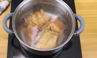 Как приготовить сборную мясную солянку по классическому пошаговому рецепту? Копченые свиные ребрышки разрежьте по межреберным промежуткам, положите их в кастрюлю для варки супа и залейте холодной водой в расчете на 6 порций супа. Поварите ребрышки течение 30 минут от начала кипения на небольшом огне и под прикрытой крышкой.